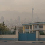 نمای ساختمان مدرسه و افق مه‌آلود تهران در روزهای آلودگی هوا و احتمال تعطیلی مدارس